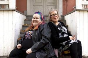 Hymyilevät äiti ja tytär istuvat portailla