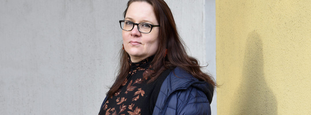 FinFamin Työ tukee -kampanjakuva Nainen harmaata taustaa vasten_kuva Marika Finne