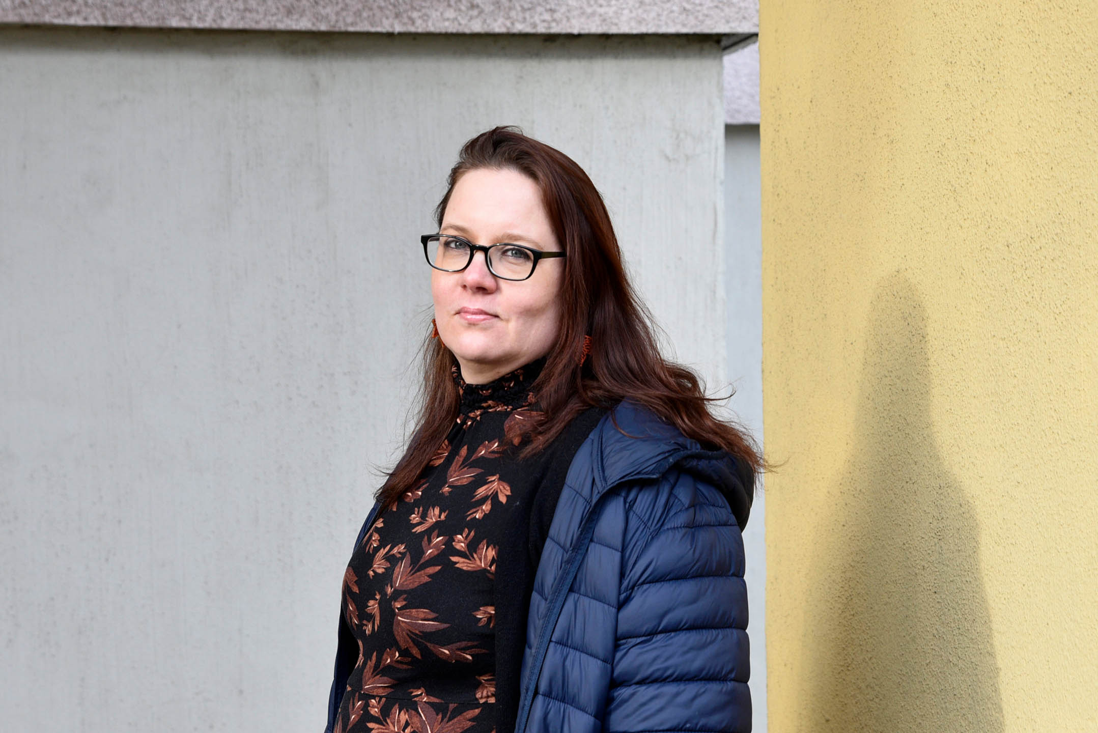 FinFamin Työ tukee -kampanjan kuva_Nainen seisoo harmaan taustan edessä