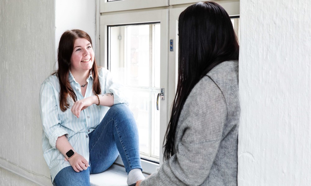 Kaksi naishenkilöä istuu ikkunalaudalla