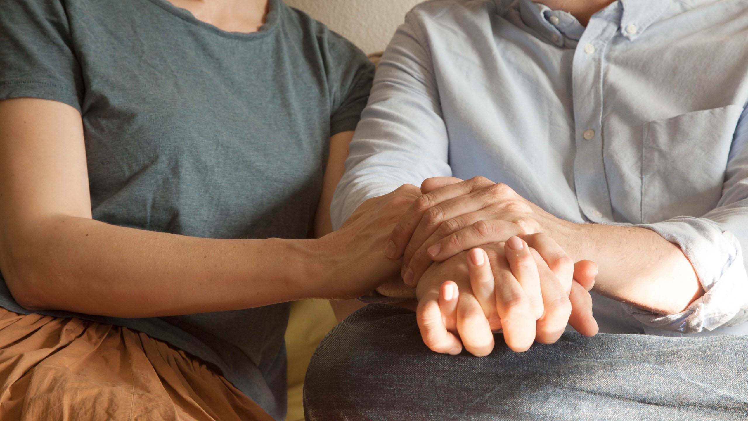 Kaksi ihmistä pitää toisiaan kädestä molemmin käsin